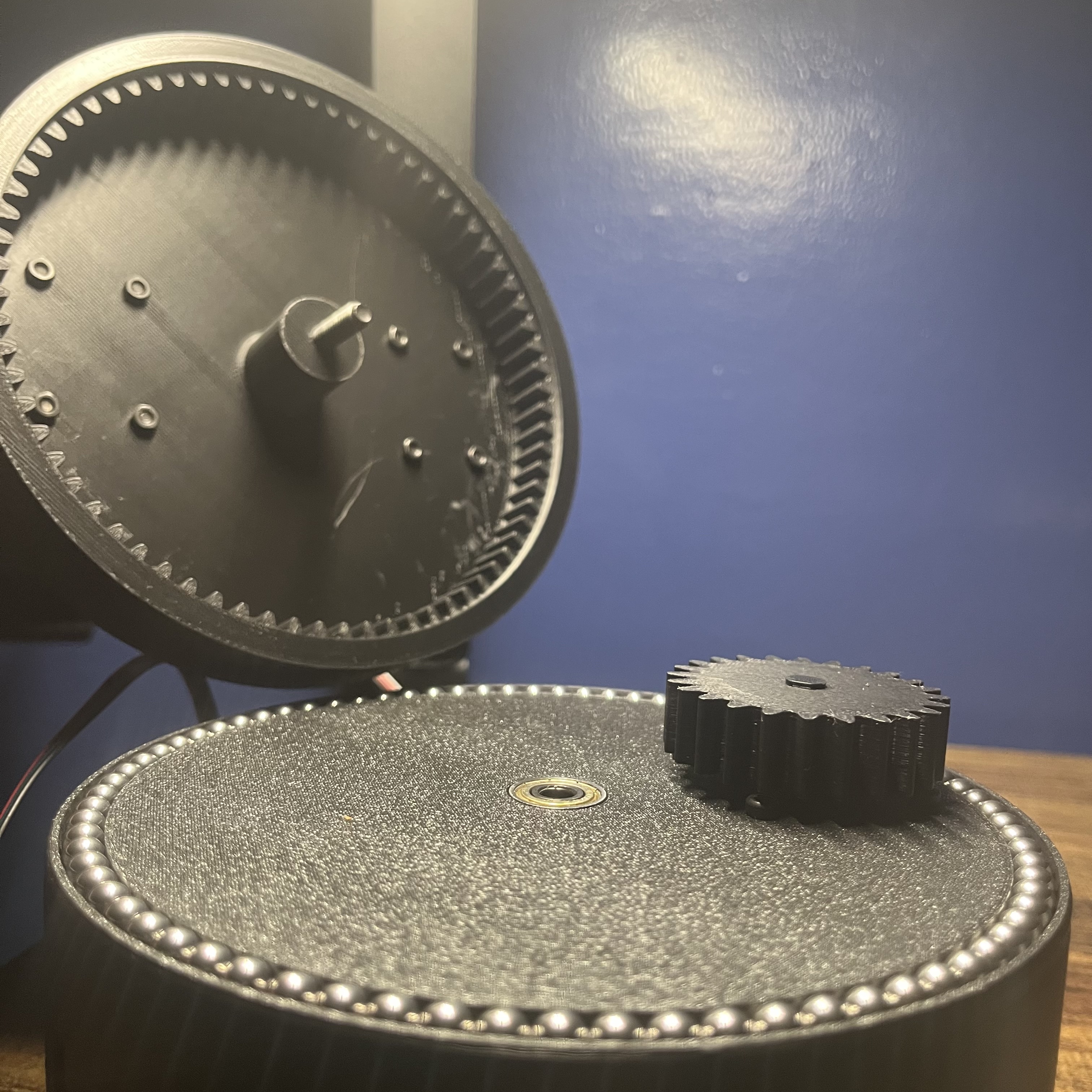 DUNCE base joint opened to show the internal ring gear in the lifted lid, the spur gear, and the stainless-steel balls around the base raceway